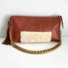 Rust leather bag with cream shearling accents, a chunky removable shoulder chain, a tassel zipper detail, and leather lining with an interior pocket.