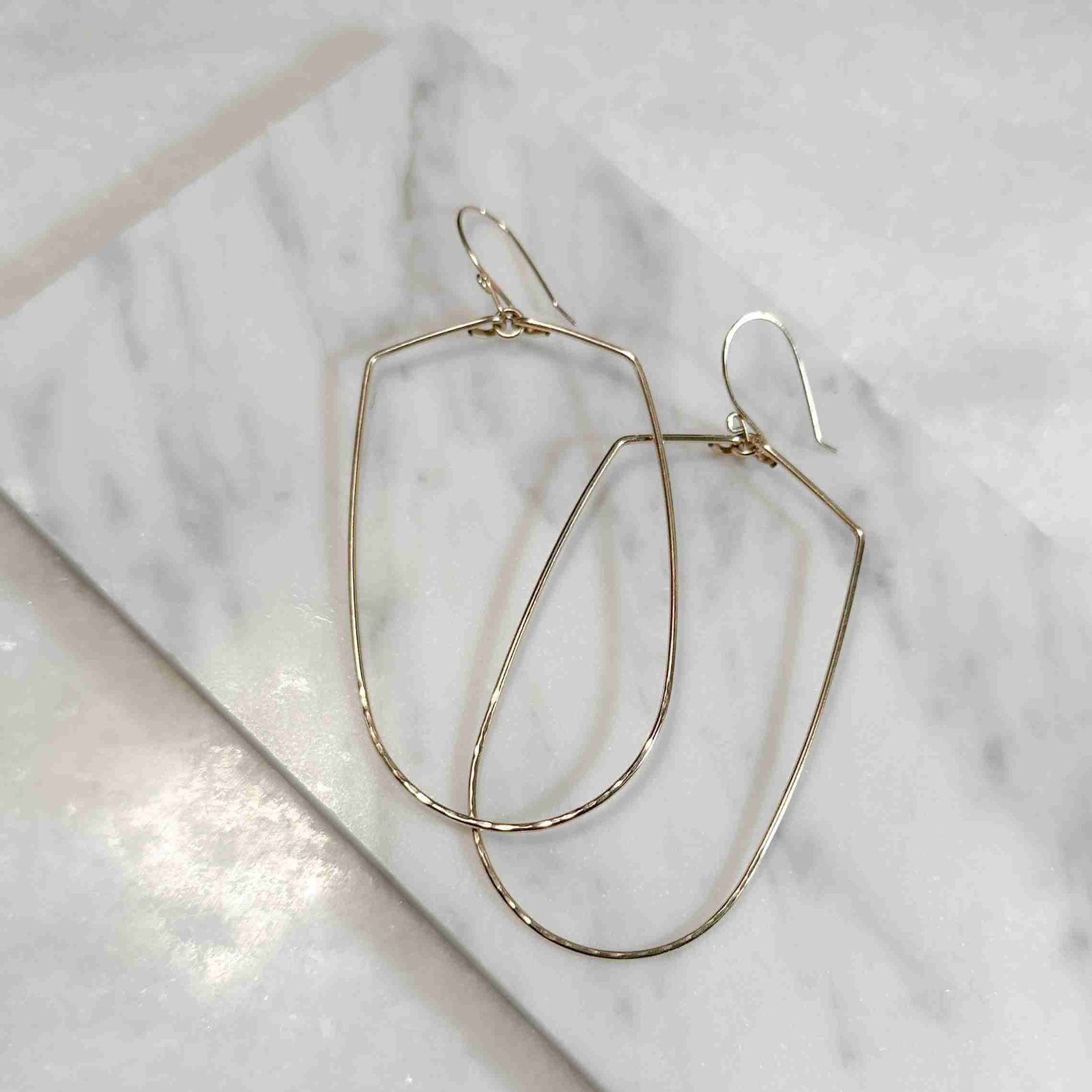 Joy Handcrafted, elongated geometric earrings in 14k gold fill or sterling silver, featuring a hammered bottom for added texture.