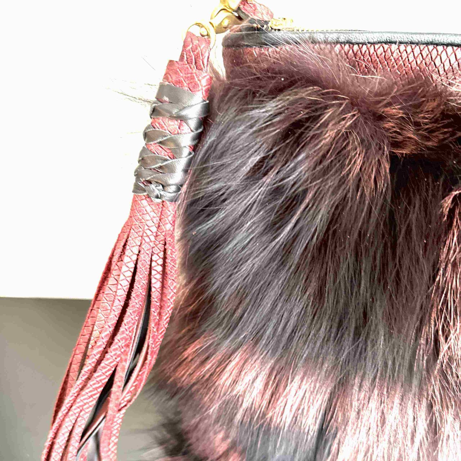 Mercer Fox Fur Clutch Bag with black and magenta fur, brass zipper closure, and magenta lining, displayed on a modern surface.