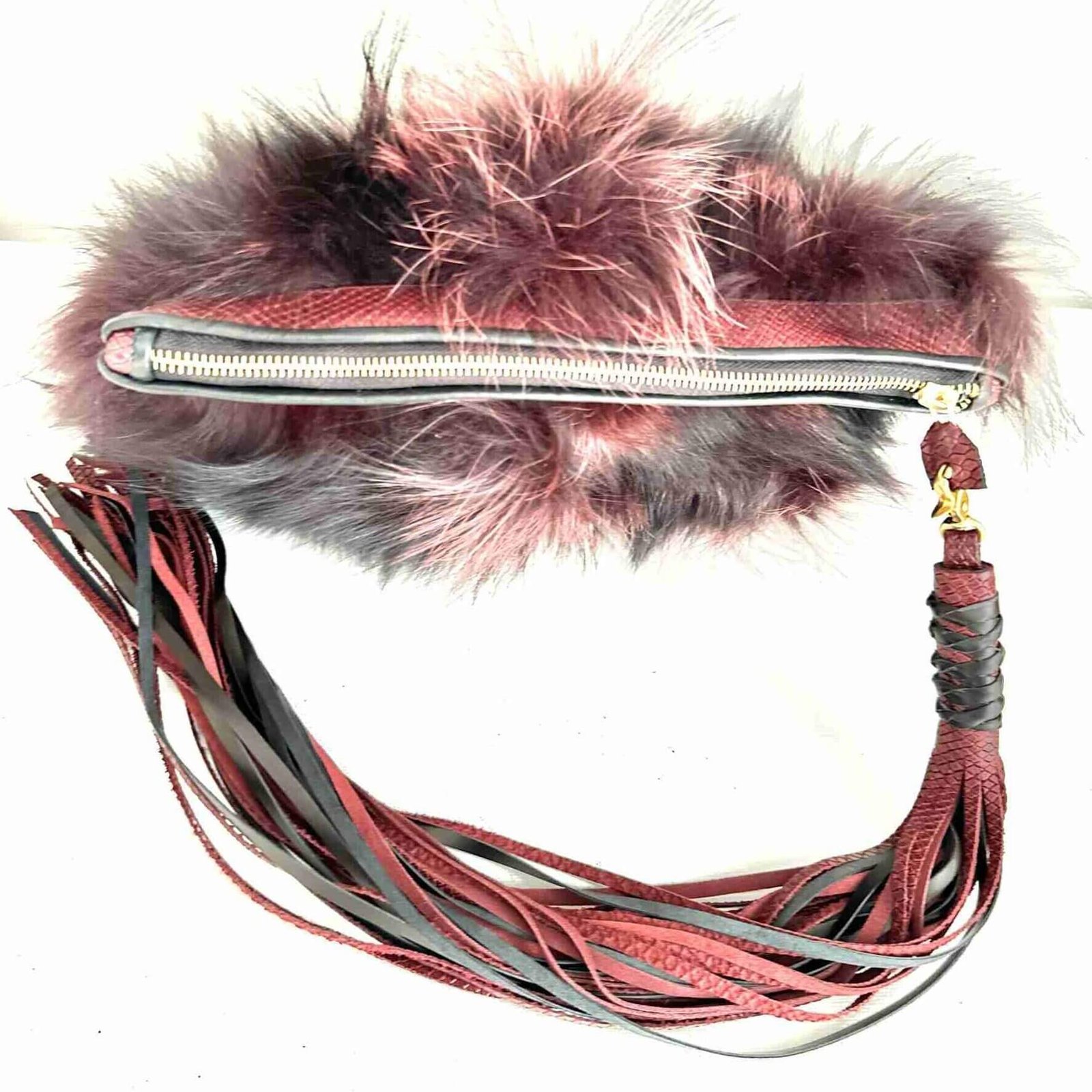 Mercer Fox Fur Clutch Bag with black and magenta fur, brass zipper closure, and magenta lining, displayed on a modern surface.
