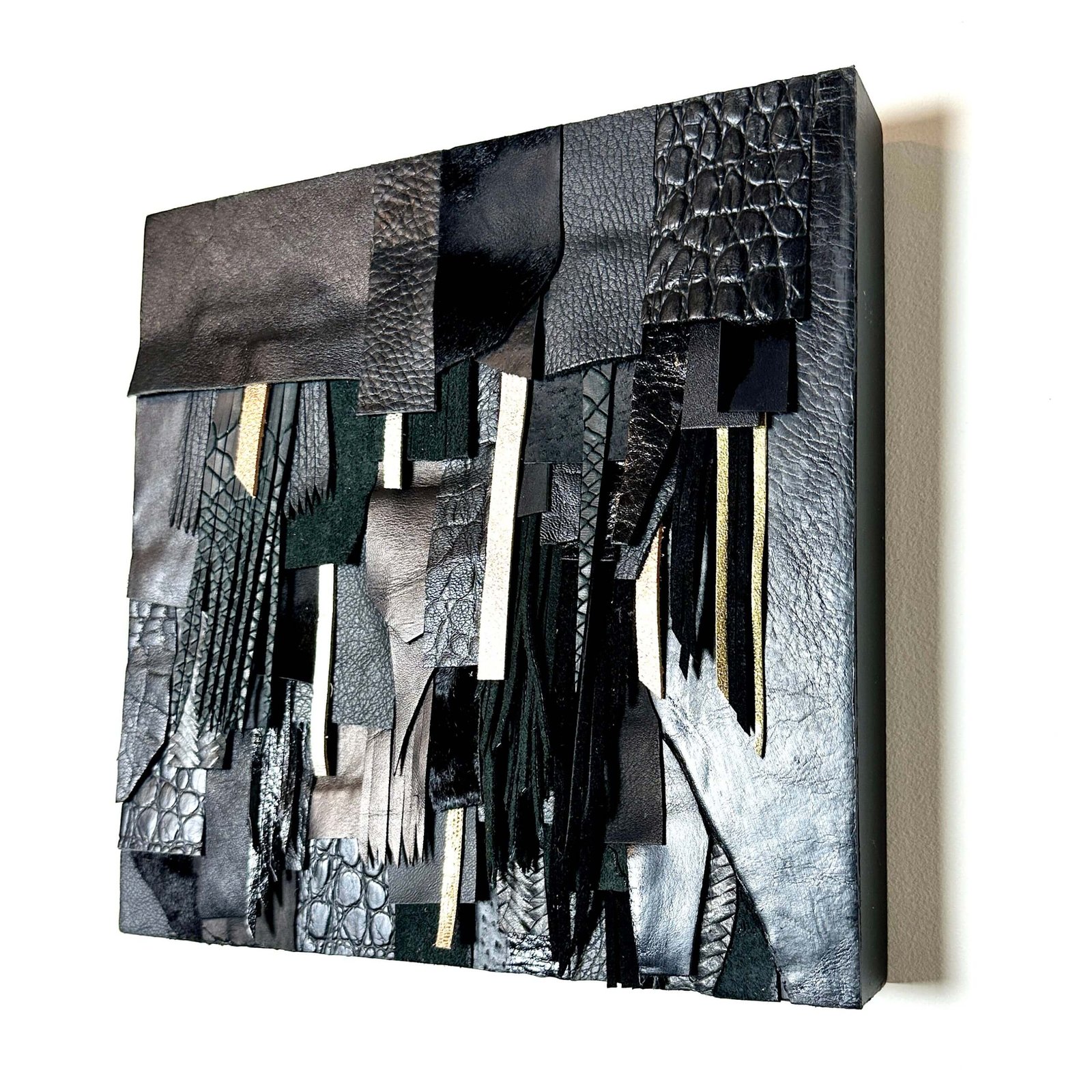 Abstract wall art made from black and textured leather scraps on wood